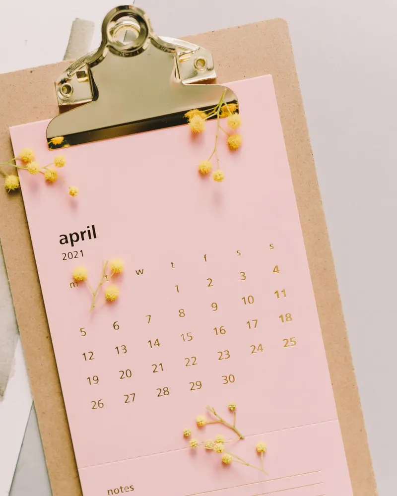 Un calendario de mes rosa sujeto a una tabla con pinza.