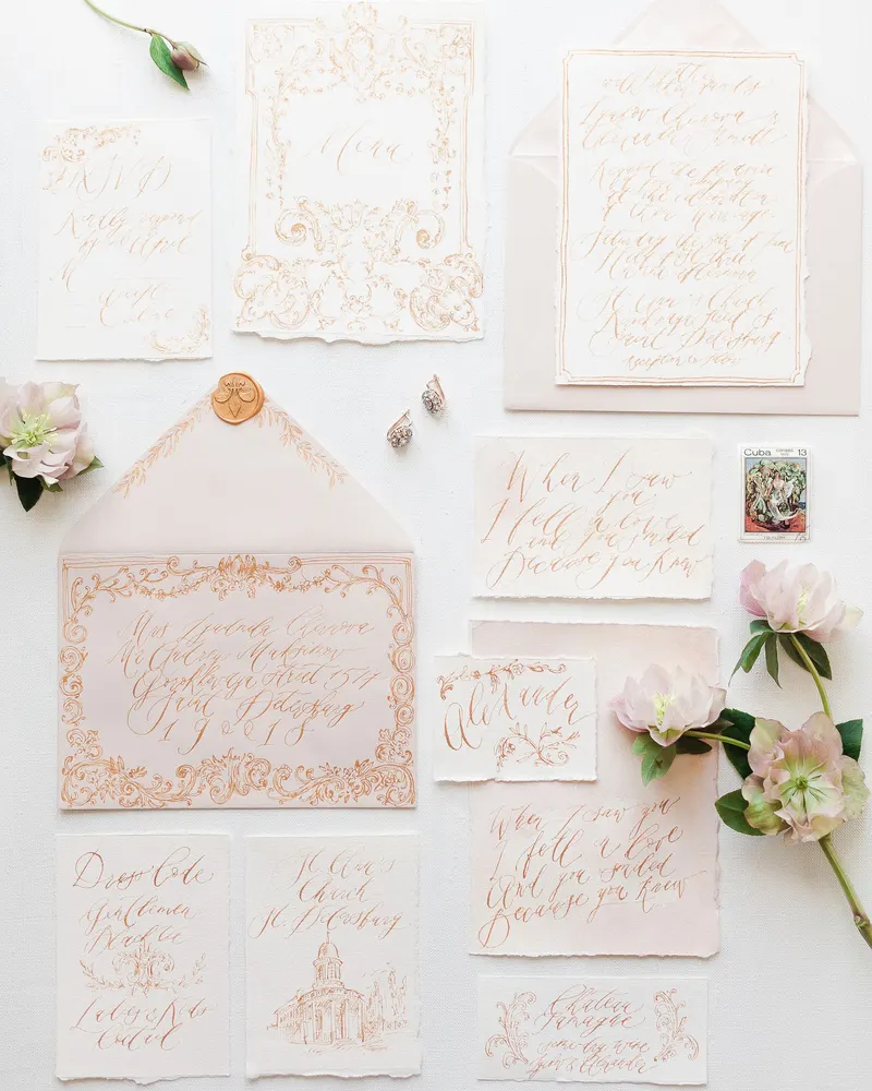 Un juego de invitaciones con caligrafía, sobres y flores.